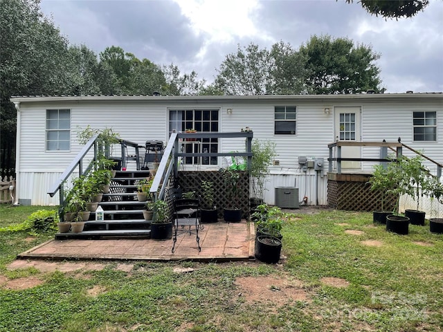 rear view of house with cooling unit, a wooden deck, and a lawn