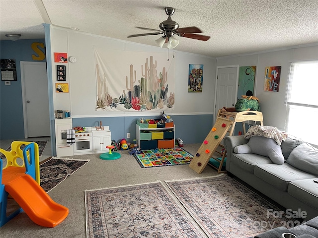 recreation room with ceiling fan, a textured ceiling, and carpet flooring