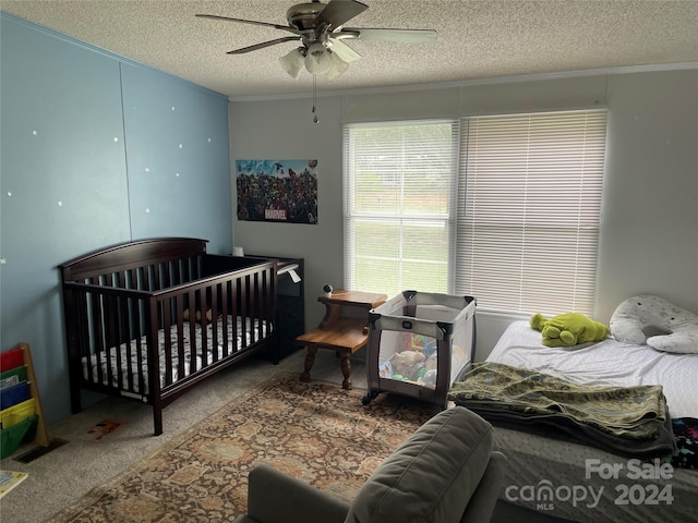 bedroom featuring ceiling fan, crown molding, a textured ceiling, and carpet