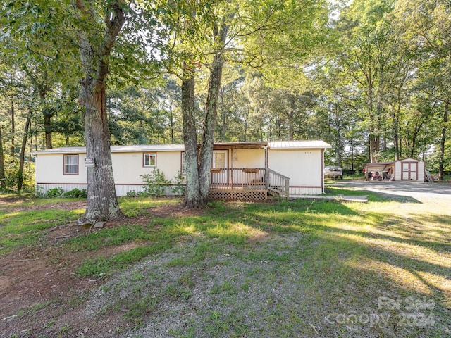 manufactured / mobile home with a front lawn and a storage shed