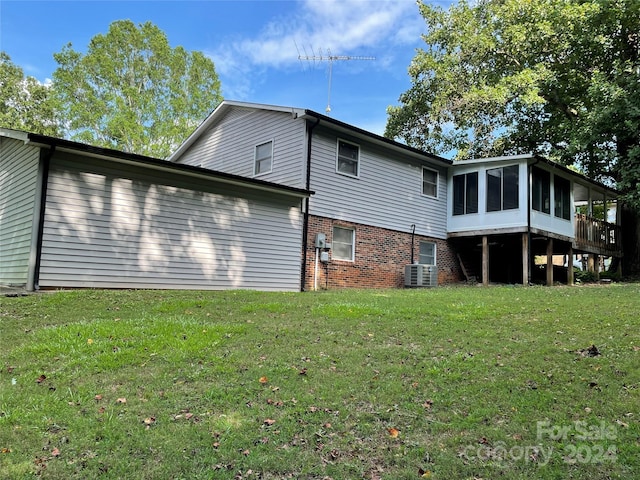 rear view of property featuring a lawn, central AC, and a sunroom