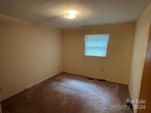 carpeted spare room with a textured ceiling