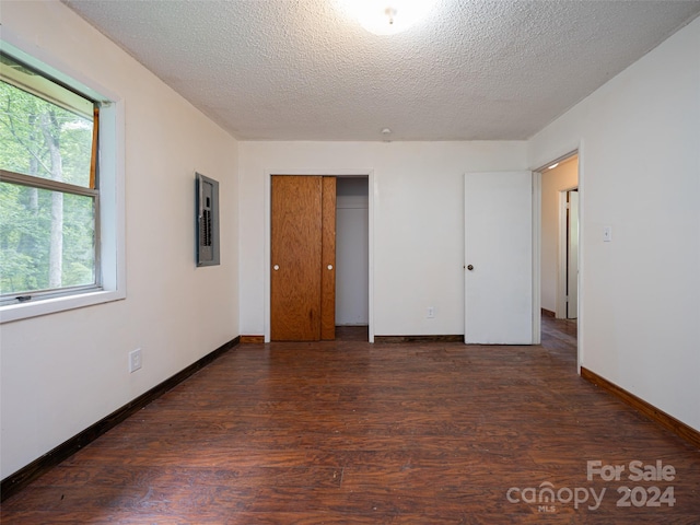 unfurnished bedroom with dark wood-type flooring, a textured ceiling, and a closet