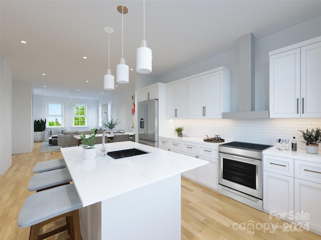 kitchen featuring sink, wall chimney range hood, white cabinets, and stainless steel appliances