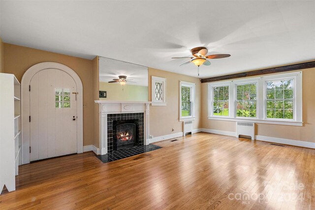 unfurnished living room featuring radiator heating unit, ceiling fan, and light wood-type flooring