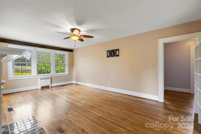 empty room featuring ceiling fan, light hardwood / wood-style floors, and radiator heating unit