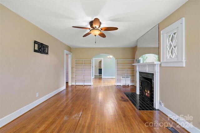 unfurnished living room featuring a fireplace, wood-type flooring, and ceiling fan