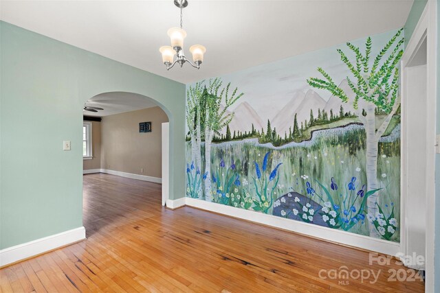 spare room with an inviting chandelier and hardwood / wood-style floors