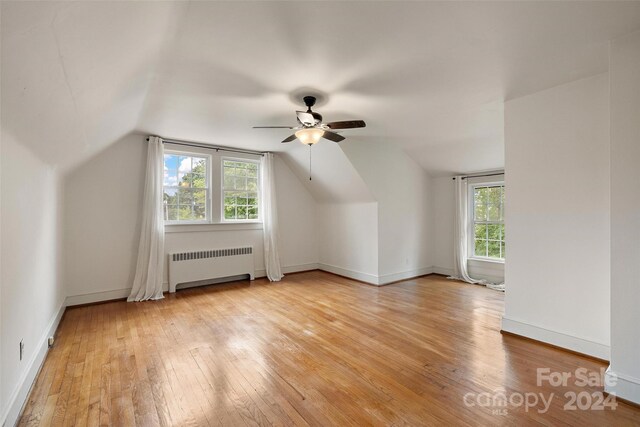 bonus room featuring lofted ceiling, light hardwood / wood-style floors, radiator, and plenty of natural light