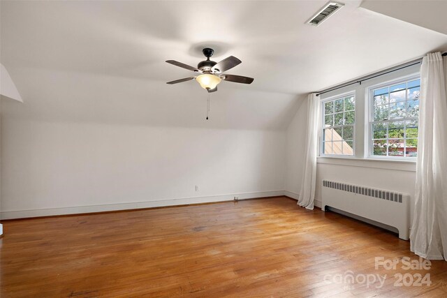 bonus room with light hardwood / wood-style floors, radiator, vaulted ceiling, and ceiling fan