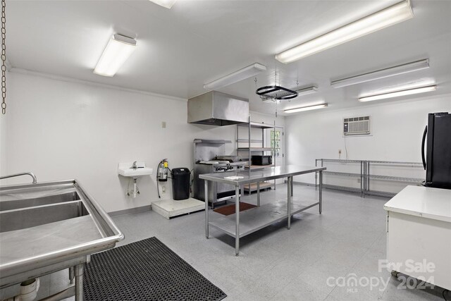 kitchen featuring a wall unit AC, black fridge, tile patterned flooring, and sink