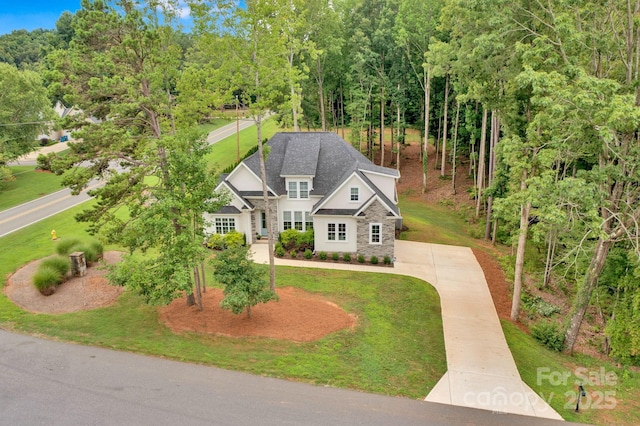 view of front of property with a front yard, stone siding, and concrete driveway