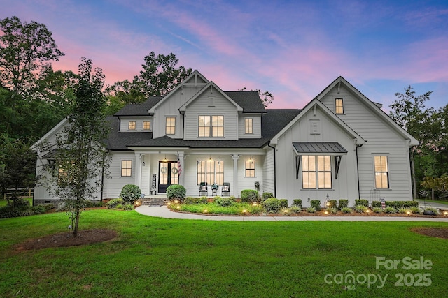 modern farmhouse style home with a lawn and covered porch