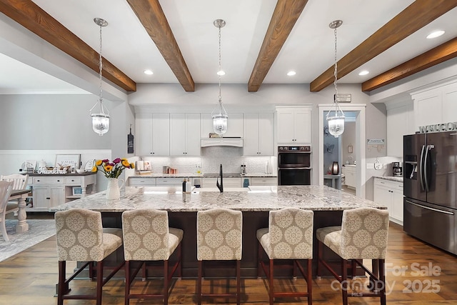 kitchen featuring pendant lighting, a spacious island, stainless steel fridge with ice dispenser, a kitchen bar, and white cabinetry