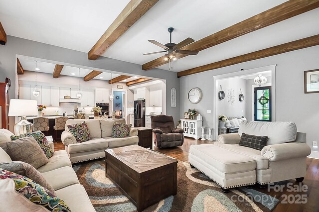 living room with beamed ceiling, ceiling fan with notable chandelier, and dark hardwood / wood-style flooring