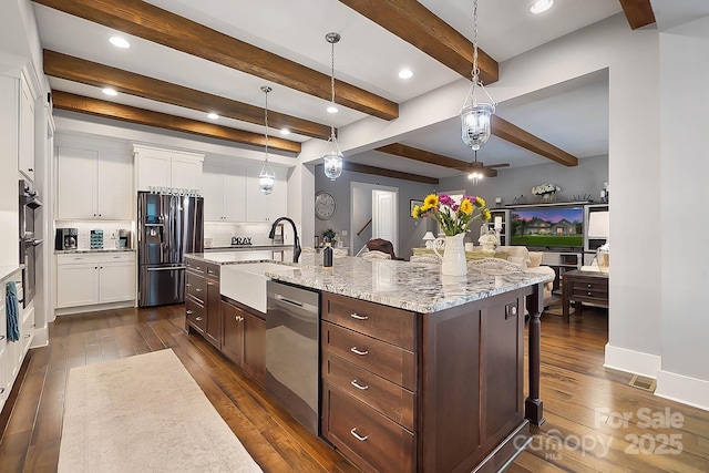 kitchen with a center island with sink, sink, hanging light fixtures, appliances with stainless steel finishes, and white cabinetry