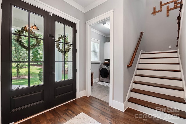 foyer with dark hardwood / wood-style flooring, washer / dryer, ornamental molding, and french doors