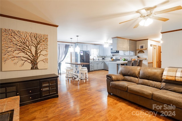 living room with ornamental molding, sink, ceiling fan, and light wood-type flooring