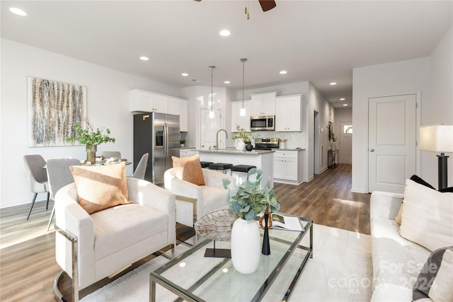 living room with sink, hardwood / wood-style floors, and ceiling fan