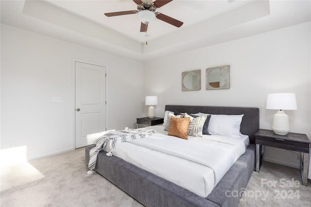 carpeted bedroom featuring ceiling fan and a tray ceiling