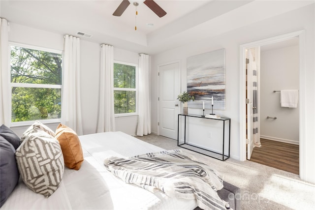 carpeted bedroom featuring ceiling fan and a tray ceiling