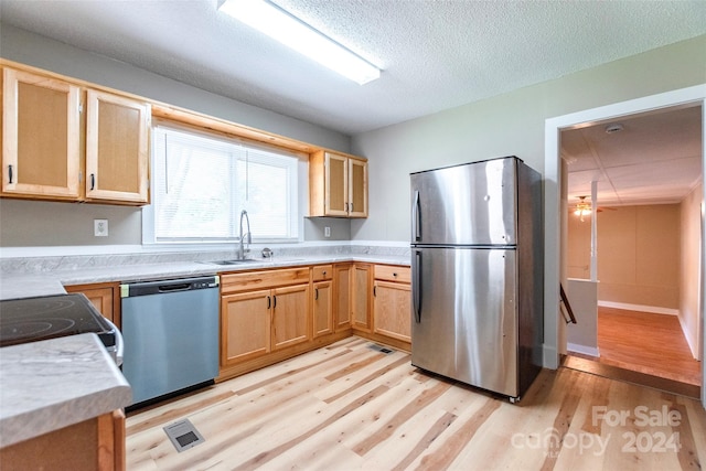 kitchen featuring a textured ceiling, stainless steel appliances, light hardwood / wood-style floors, sink, and ceiling fan