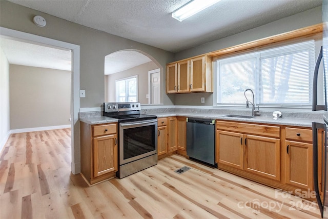 kitchen featuring light wood-type flooring, appliances with stainless steel finishes, sink, and a textured ceiling