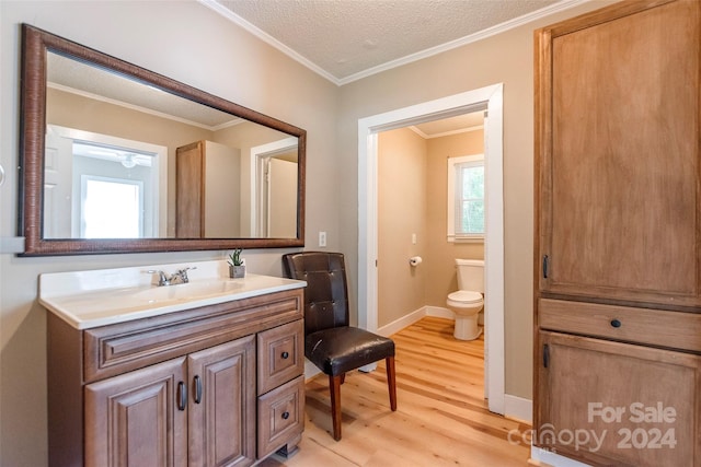 bathroom with toilet, vanity, wood-type flooring, crown molding, and a textured ceiling