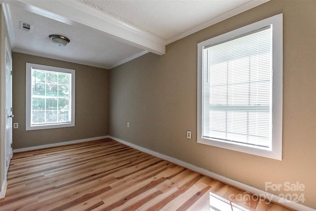 unfurnished room with a textured ceiling, crown molding, beamed ceiling, and light wood-type flooring