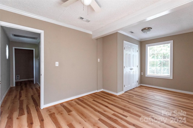 empty room with ceiling fan, a textured ceiling, crown molding, and light wood-type flooring