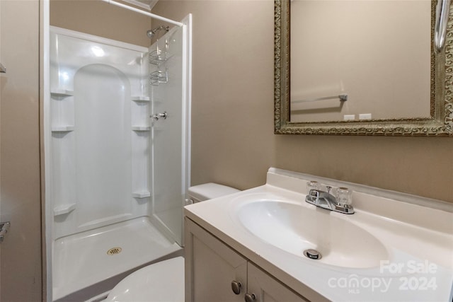 bathroom featuring toilet, vanity, and a shower