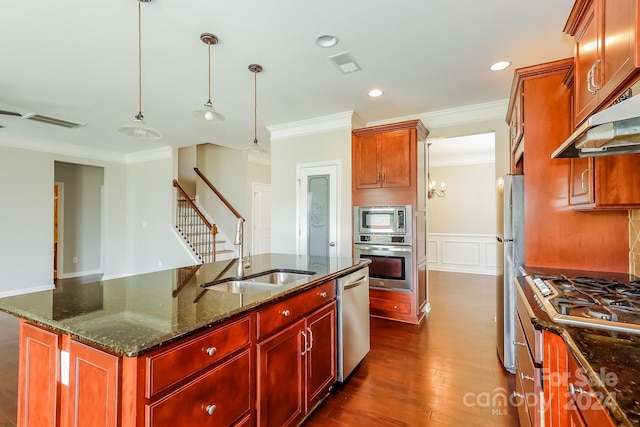 kitchen with pendant lighting, sink, dark stone countertops, stainless steel appliances, and an island with sink