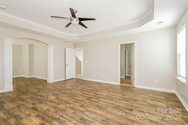 unfurnished room with crown molding, ceiling fan, hardwood / wood-style floors, a raised ceiling, and ornate columns