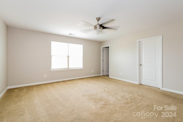 spare room featuring light colored carpet and ceiling fan