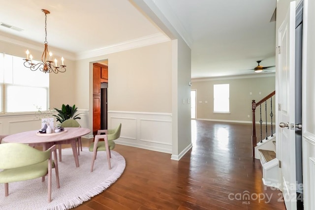 dining area featuring dark wood-type flooring, ornamental molding, and a notable chandelier