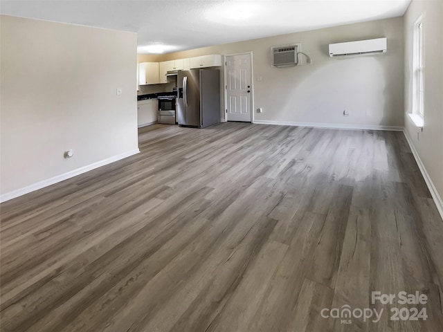 unfurnished living room with light wood-type flooring and a wall mounted AC