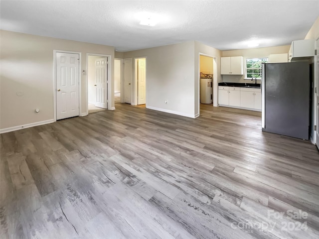 unfurnished living room featuring water heater, a textured ceiling, and light hardwood / wood-style flooring