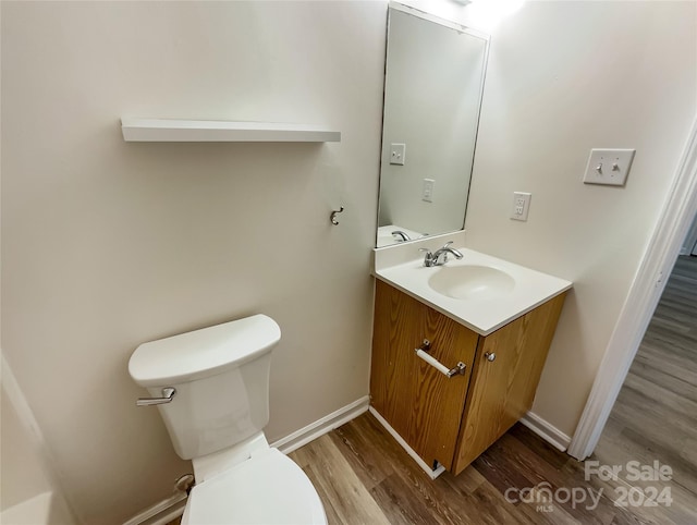 bathroom featuring hardwood / wood-style flooring, toilet, and vanity