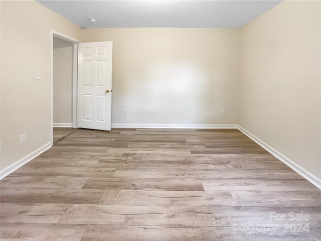 unfurnished room with a textured ceiling and light hardwood / wood-style flooring