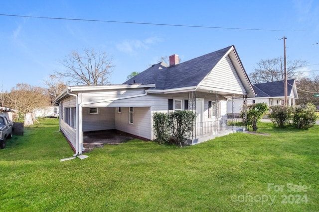 rear view of property with a porch, a carport, and a lawn