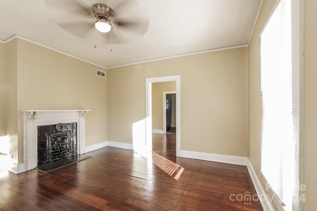 unfurnished living room with dark wood-type flooring, plenty of natural light, and crown molding