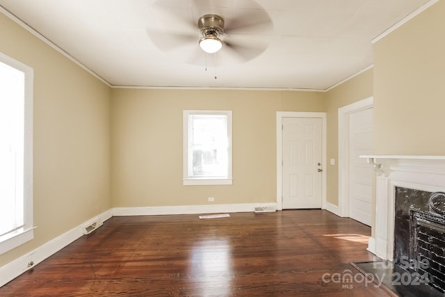 unfurnished living room with ceiling fan, dark wood-type flooring, crown molding, and a fireplace