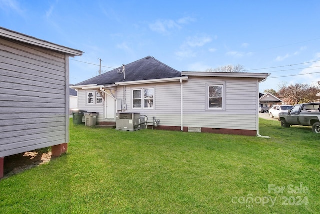 rear view of property featuring cooling unit and a yard