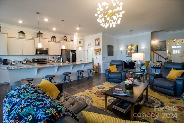 living room featuring a notable chandelier, dark wood-type flooring, and crown molding