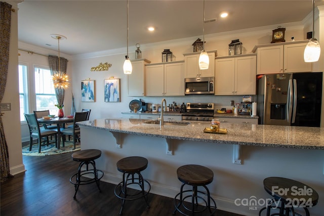 kitchen featuring stainless steel appliances, light stone countertops, decorative light fixtures, sink, and white cabinetry