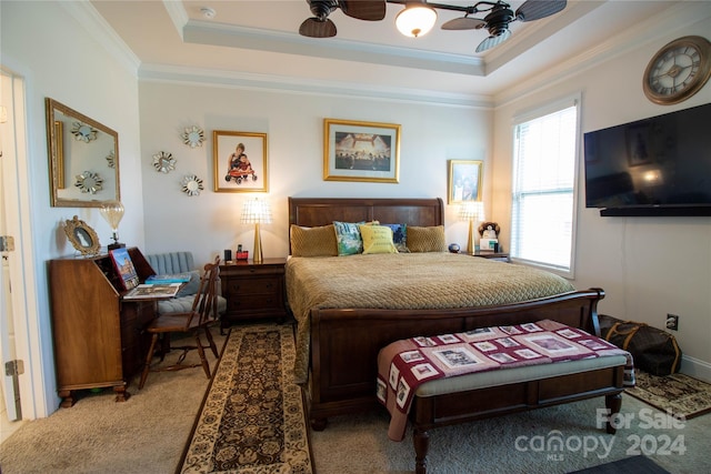 carpeted bedroom with a tray ceiling, ceiling fan, and crown molding