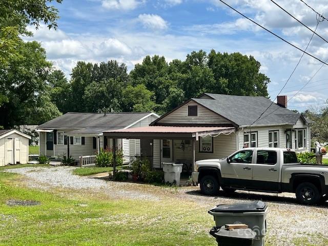 view of front of house featuring a front lawn, a carport, and a shed