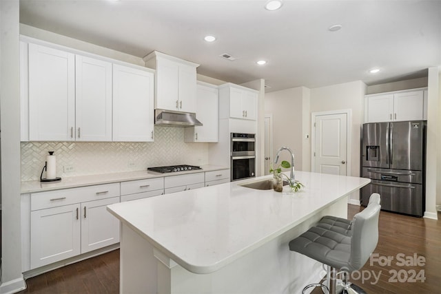 kitchen featuring appliances with stainless steel finishes, white cabinets, a center island with sink, and dark hardwood / wood-style flooring