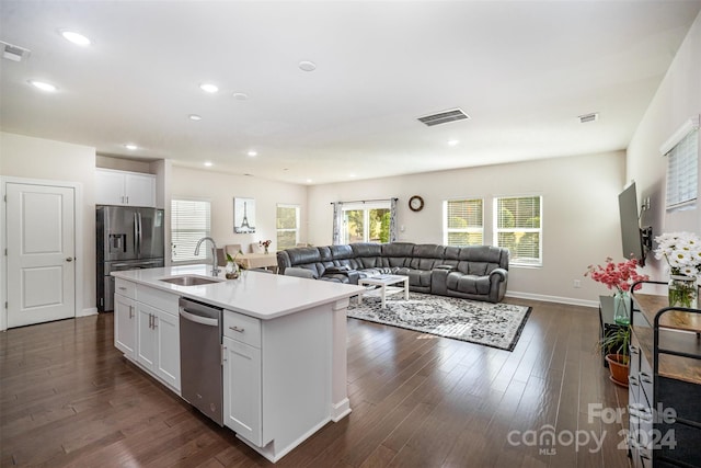 kitchen with sink, appliances with stainless steel finishes, a kitchen island with sink, and white cabinetry