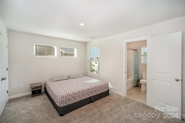 bedroom with ensuite bathroom and light colored carpet